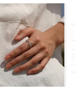 Detail of dainty sterling silver moissanite ring worn on hand with elegant linen outfit