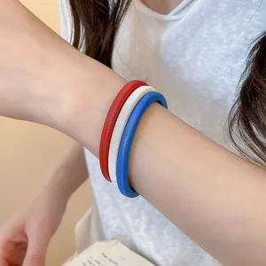 Dettaglio di un set di tre braccialetti a catena a molla in rosso, bianco e blu