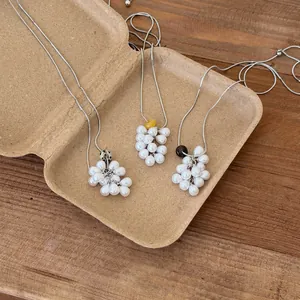 Close-up of grape cluster pearl necklaces with colorful natural stone beads on wood.