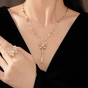 Detailopname van een elegante gouden vlindersleutel hanger ketting en bijpassende ring