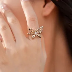 Elegante gouden vlinderring met heldere zirkoon gedragen door een vrouwelijk model.