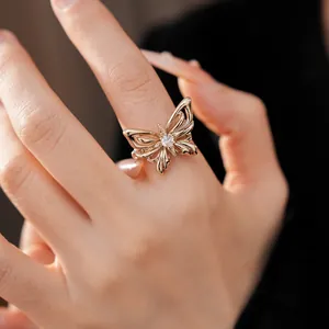 Gedetailleerd overzicht van een elegante gouden vlinderring met zirkoon op een vrouwenhand.