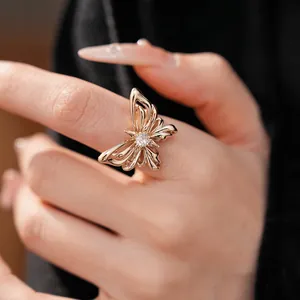 Gedetailleerde close-up van een elegante vergulde vlinderring met een zirkoon op de vinger