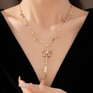 Close-up van een gouden ketting met vlindersleutel hanger en zirkoon op zwart kleed