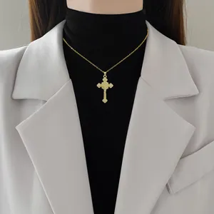 Elegant gold cross necklace with sparkling zircon crystals worn on a female model