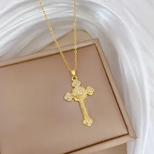 Close-up of gold-plated cross necklace with zircon stones on champagne satin fabric