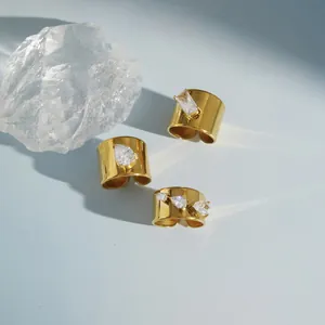 Detailweergave van vergulde brede bandringen met heldere zirkoniasteen versiering.