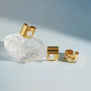 Detailweergave van gouden roestvrijstalen brede ringen met heldere zirkonia-stenen.