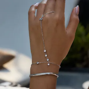 Détail d'un ensemble de bijoux de main argentés avec un bracelet serpent sur une main.
