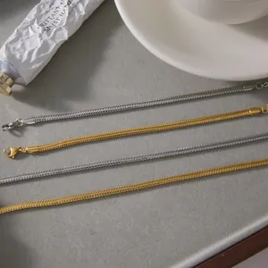 Gros plan de chaînes en os de serpent dorées et argentées dans un décor minimaliste
