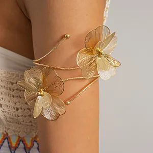 Detail view of a large gold wire-work floral arm cuff on a female model's upper arm.