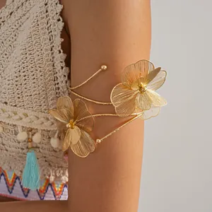 Close-up detail of a gold metal flower open arm cuff worn on a model's upper arm