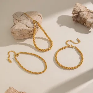 Macro detail of 18K gold-plated stainless steel bead bracelets with lobster clasp and tag