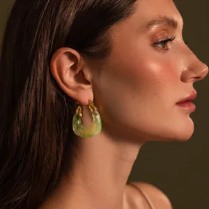 Detail view of large U-shaped earrings in gold stainless steel and marbled green resin.
