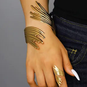 Détail d'un ensemble manchette et bague dorées sculpturaux aux lignes abstraites