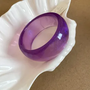 Primo piano dettagliato di bracciale in resina viola con glitter fini in piatto a conchiglia