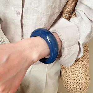 Primo piano dettagliato di un bracciale in resina lucida blu scuro indossato da una donna.