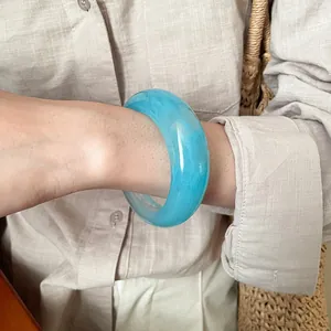 Dettaglio di un bracciale a cerchio in resina blu marmorizzata dal design geometrico