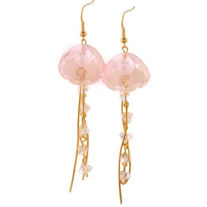 Détail des boucles d'oreilles méduses roses translucides avec accents dorés et perles.