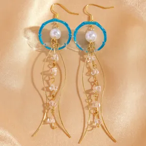 Détail des boucles d'oreilles méduse avec résine bleue, perles et cristaux