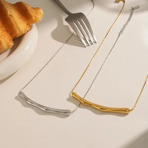 Detail of minimalist wavy bar pendant necklaces in gold and silver on warm home setting