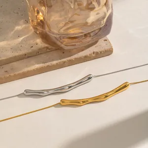 Macro detail of minimalist gold and silver curved bar necklaces on organic stone background
