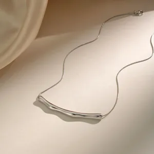 Macro shot of silver polished irregular curved tube pendant on a snake chain necklace