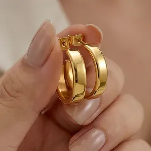 Macro shot of chunky gold-plated stainless steel C-shaped hoop earrings with mirror finish