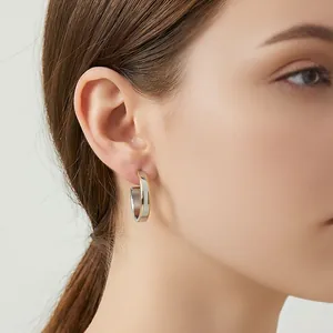 Macro side view of a model wearing minimalist gold and silver C-shaped hoop earrings
