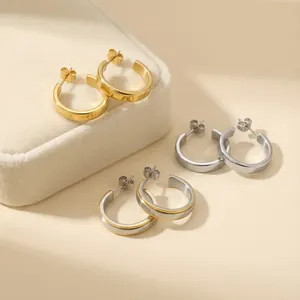 Detailed view of polished C-shaped stainless steel hoop earrings in gold and silver