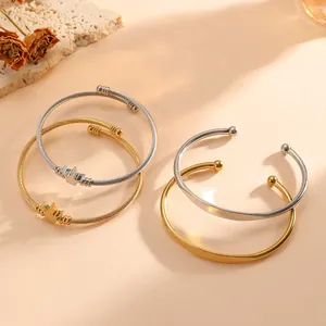 Dettaglio di bracciali a corona e aperti in acciaio inossidabile oro e argento