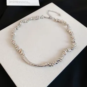 Detailopname van een zilverkleurige onregelmatige metalen choker met een ruwe textuur