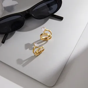Close-up macro view of two luxury gold zircon open rings displayed on a silver laptop with sunglasses