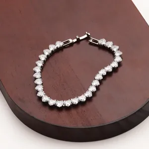Detailed close-up of heart-shaped zircon tennis bracelet on dark wood display stand