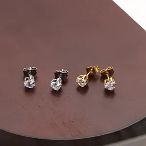 Macro shot of gold and silver heart-shaped cubic zirconia stud earrings on a wooden tray