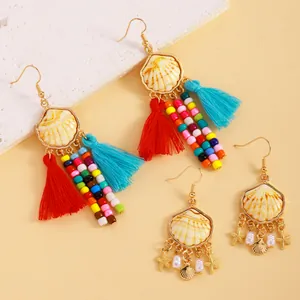 Vue détaillée de boucles d'oreilles bohèmes avec pompons colorés et breloques étoile de mer.