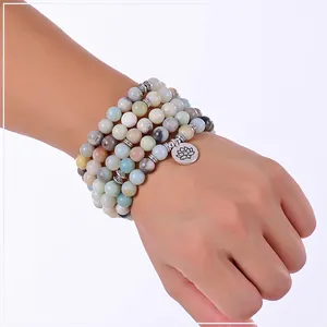 Primo piano del braccialetto mala in perle di amazzonite con ciondolo a fiore di loto.