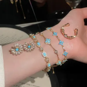 Elegante set di gioielli dorati con fiori azzurri e cristalli scintillanti sul polso