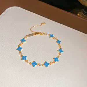 Dettaglio di un bracciale dorato con fiori in resina blu e pietre scintillanti.