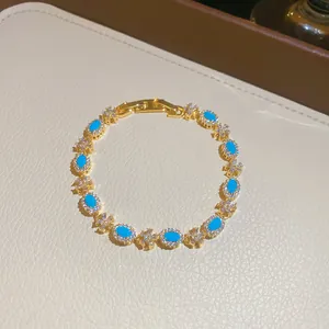 Elegante bracciale dorato con resina turchese ovale e dettagli floreali in cristallo