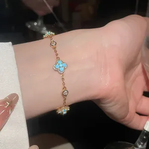 Primo piano di un elegante bracciale in oro con pietre floreali turchesi sul polso