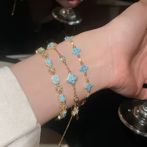 Dettaglio di eleganti bracciali in oro con fiori in resina blu e pietre luccicanti