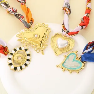 Dettaglio di choker in sciarpa di seta con ciondoli a cuore e occhio bohémien.