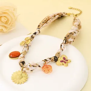 Dettaglio della collana in seta leopardata con ciondoli a girasole e farfalla dorata