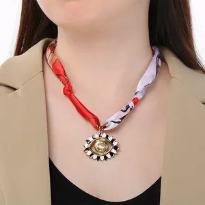 Dettaglio del choker bohémien in seta stampata con ciondolo a forma di occhio su modella