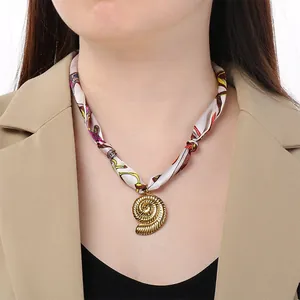 Dettaglio di un choker in seta stampata bohémien con pendente a conchiglia dorata