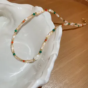Primo piano di una collana di perline fatta a mano con pezzi di conchiglia e perla barocca.