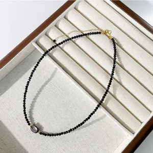 Dettaglio di un girocollo di perline nere con ciondolo a testa di gatto in scatola regalo.