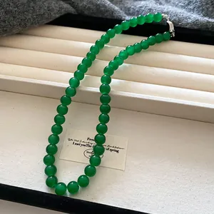 Primo piano di una collana di perle di vetro verdi su un vassoio per gioielli bianco