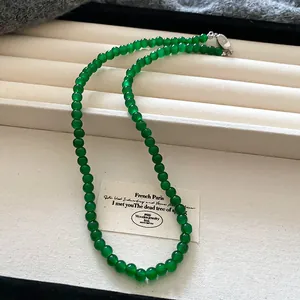 Dettaglio di un'elegante collana di perle di vetro verde con chiusura in acciaio.
